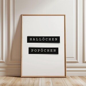 May include: A framed print with the words "Hallöchen" and "Popöchen" in black text on a white background.