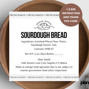 May include: A white label with black text on a brown wooden bowl. The label reads "Fresh Baked Fresh Baked Fresh Bake Bread House Sourdough Bread Ingredients: Enriched Wheat Flour, Water, Sourdough Starter, Salt. Contains: WHEAT Net WT: 3 oz | Best Before ______ Alma Smith 2261 Koontz Lane | Los Angeles CA 90014 Made in cottage food operation that is not subject to routine government food safety inspections Fresh Baked Fresh Baked Fresh Baked Fresh Baked Project pismo"