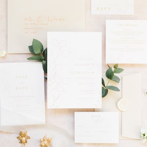 Wedding stationery flat lay with invitation, save the date, details and RSVP card with pale stone colour envelopes, gold calligraphy address and white wax seal. Designs feature delicate hand drawn winter botanicals. Text is clean, modern and minimal