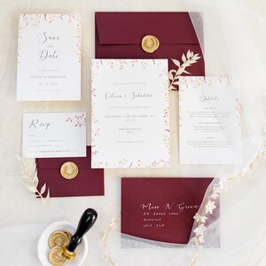 Wedding stationery suite with 5x7 invitation, A6 save the date, details card, A7 rsvp car and burgundy envelopes with white calligraphy address and gold wax seals. Autumnal design with watercolour leaves in burnt orange, red and deep purple.