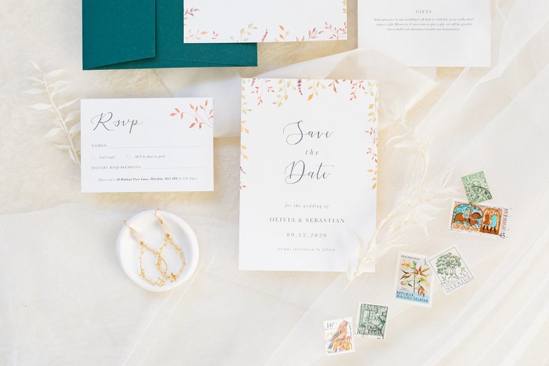 Wedding stationery flat lay with autumn save the date design. Features watercolour autumn leaves in burnt orange, gold and burgundy, grey text and modern calligraphy script. Minimal and modern design printed on luxury white paper with texture