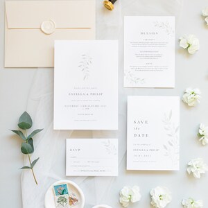 Wedding stationery suite flat lay with 5x7 invitation, A6 save the date, details card, A7 rsvp card, neutral envelope with white wax seal. Minimal watercolour foliage design in pale green. Modern serif font for all text in grey. Printed on luxe paper