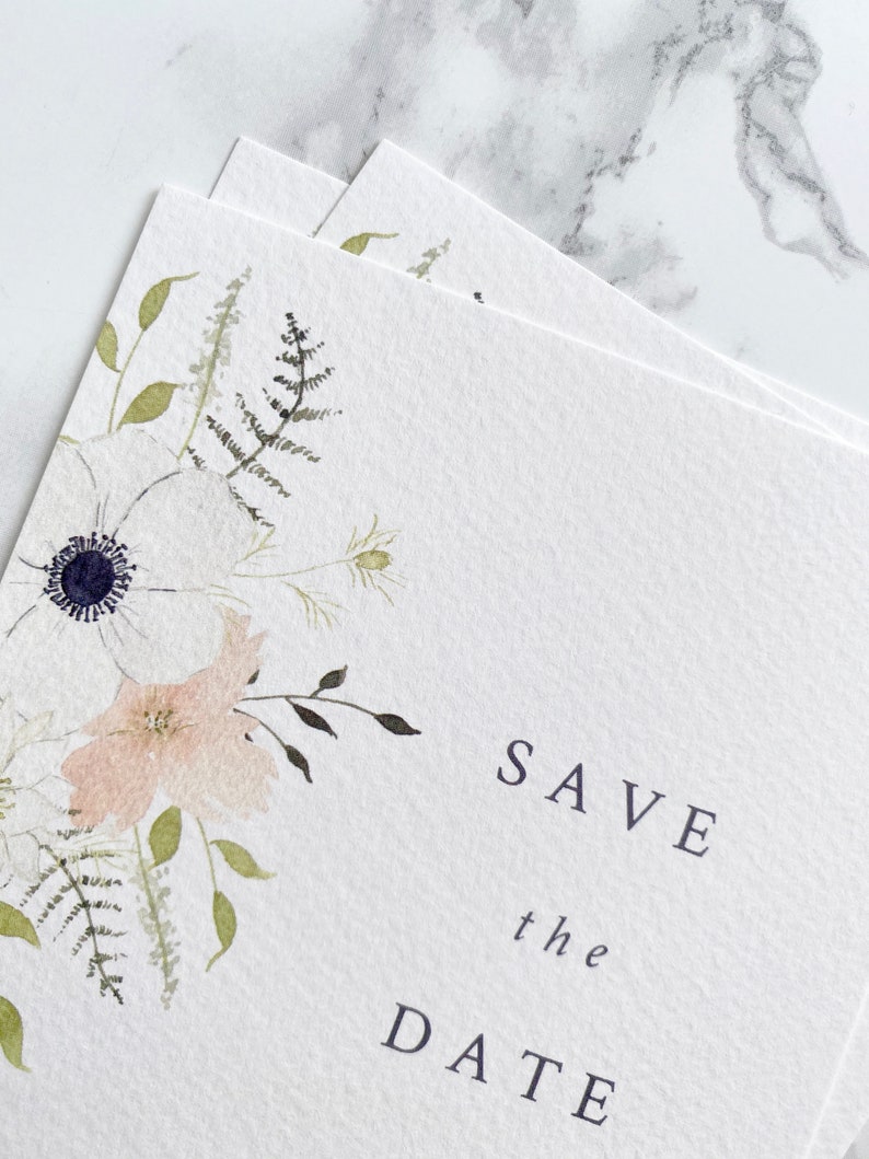 Close up of illustration on A6 save the date card. Watercolour floral illustration with white anemone and peach and cream flowers. Save the date is in aligned right in a minimal, modern style. Printed on luxury white paper.