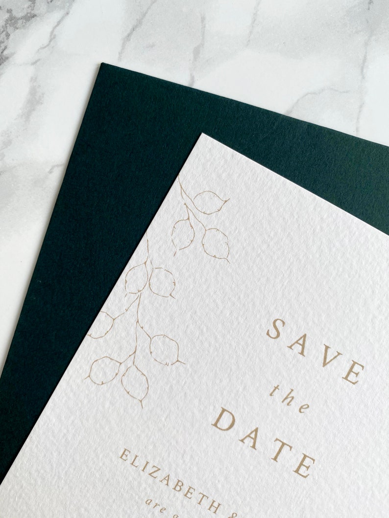 Close up of illustration detail on top corner of wedding save the date card with dark green coloured envelope. Hand drawn honesty branches in delicate line drawing style with save the date in clean and modern serif font in the centre.