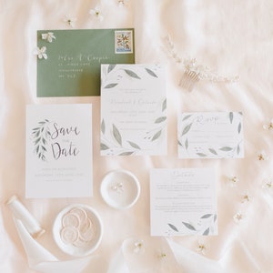 Wedding stationery suite with A6 invitation, save the date, square details card and A7 rsvp card. Sage green envelope with white calligraphy addressing and white wax seals.  Green watercolour foliage frames each design.