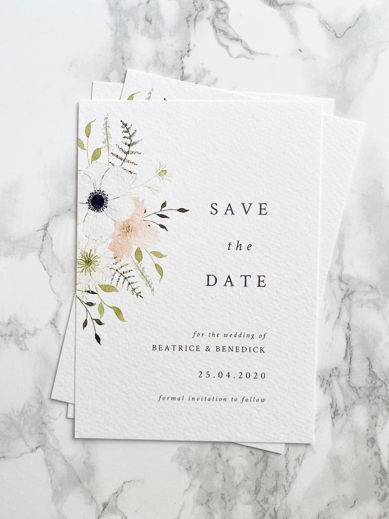 A6 portrait save the date cards with spring floral design painted in watercolour. Colours are peach, white and cream with various shades of green foliage. Text is minimal and modern in a classic serif font, aligned right.