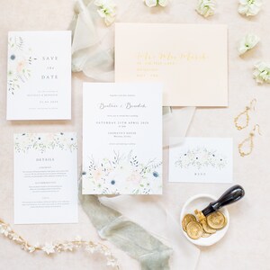 Wedding stationery flat lay with 5x7 invitation, A6 save the date, details card and A7 RSVP card with pale peach envelope, gold calligraphy addressing and gold wax seals. Designs feature spring watercolour floral design with lots of green foliage.