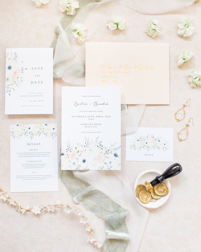 Wedding stationery flat lay with 5x7 invitation, A6 save the date, details card and A7 RSVP card with pale peach envelope, gold calligraphy addressing and gold wax seals. Designs feature spring watercolour floral design with lots of green foliage.