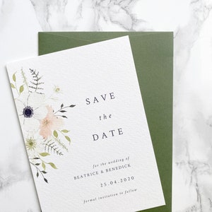 A6 portrait save the date card with sage green envelope. Design features spring watercolour florals in peach, white and cream with anemone and ranunculus. Minimal design with elegant serif font printed on luxury white textured card stock.