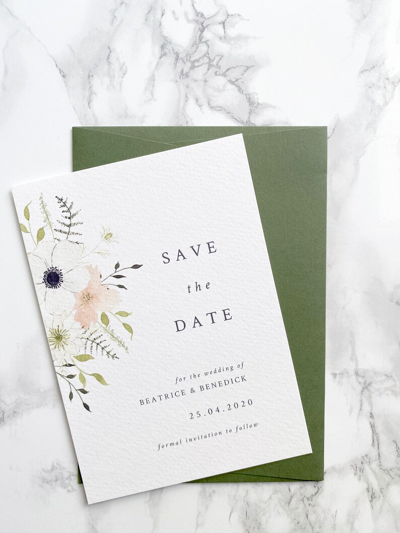 A6 portrait save the date card with sage green envelope. Design features spring watercolour florals in peach, white and cream with anemone and ranunculus. Minimal design with elegant serif font printed on luxury white textured card stock.