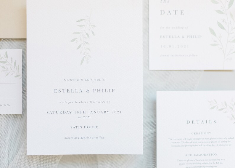 Wedding stationery flat lay with 5x7 invitation, A6 details card and save the date. Minimal design with watercolour eucalyptus branch at top with minimal text below in grey, classic serif font. Printed on luxury white textured paper