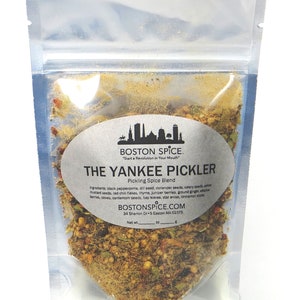 May include: A clear plastic pouch containing a blend of spices labeled "The Yankee Pickler Pickling Spice Blend". The label is white with black text and features a small illustration of the Boston skyline. The ingredients are listed on the label, including black peppercorns, dill seed, coriander seeds, celery seeds, yellow mustard seeds, red chili flakes, thyme, juniper berries, ground ginger, allspice berries, cloves, cardamom seeds, bay leaves, star anise, and cinnamon sticks.