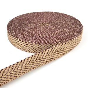 May include: A roll of woven ribbon with a herringbone pattern. The ribbon is a combination of tan and burgundy colors. The ribbon is rolled up, with a portion unrolled, showing the pattern and texture of the material.
