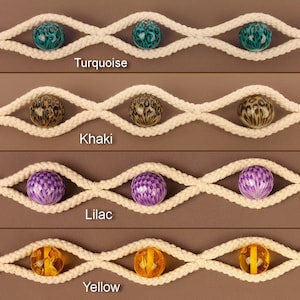 May include: Four rows of white rope with different coloured beads strung through them. The beads are turquoise with a leopard print, khaki with a leopard print, lilac with a checkered pattern, and yellow with a clear amber colour.