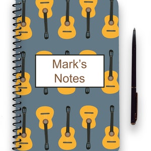 May include: A blue spiral notebook with a yellow guitar pattern and the text "Mark's Notes" on the front cover.