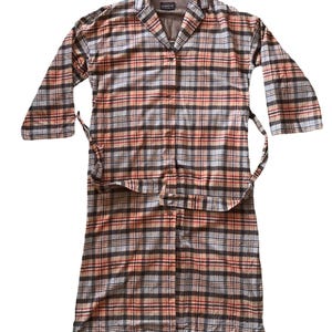 May include: A long-sleeved, button-down robe in a plaid pattern. The robe features a collar, a waist tie, and a mix of colors including brown, orange, red, and gray. The robe is made of a soft, comfortable material.