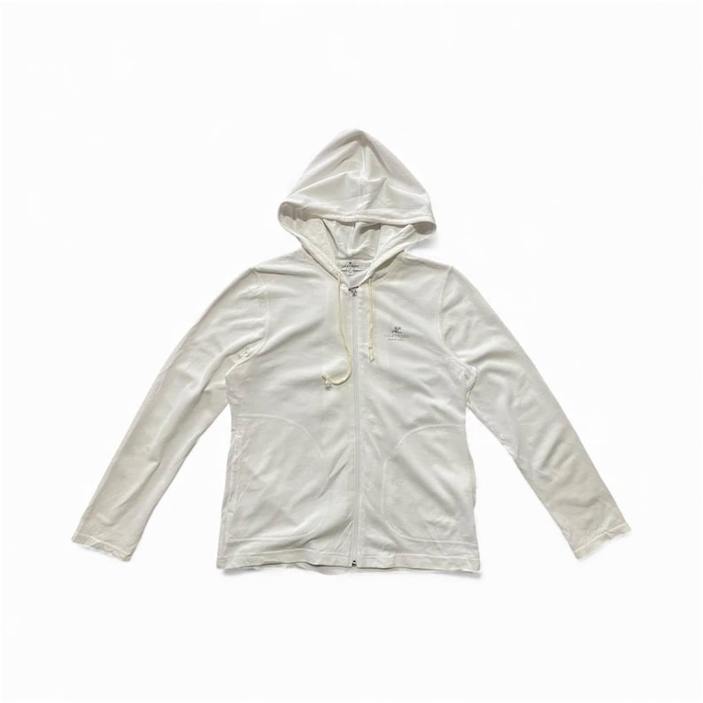 May include: A white hooded zip-up sweatshirt with long sleeves. The sweatshirt has a drawstring at the hood and a small logo on the chest. The fabric appears to be soft and comfortable.
