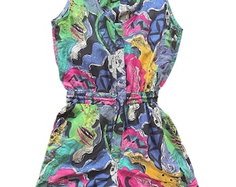 Op de afbeelding: Een mouwloze romper met een V-hals en elastische taille. De romper heeft een levendig abstract patroon in groen, blauw, roze, geel en zwart. De stof lijkt lichtgewicht en geschikt voor warm weer.