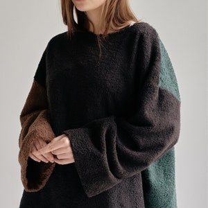 以下が含まれることがあります： ゆったりとしたシルエットの、茶色と緑のふわふわした長袖セーターです。