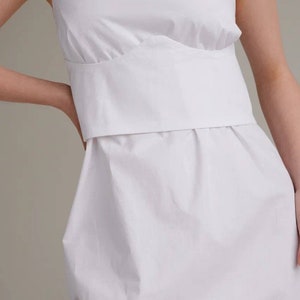 May include: A white sleeveless dress with a fitted bodice and a flowing skirt.