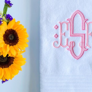 May include: White bath towel with pink embroidered monogram "ESF" in a decorative script font.