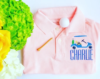 May include: Pink polo shirt with a blue embroidered golf cart and the name "Charlie" on the front.