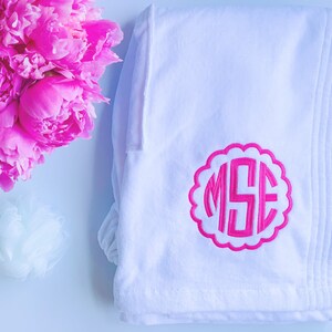 May include: White bathrobe with a pink monogram of the letters "MSE" in a scalloped circle.