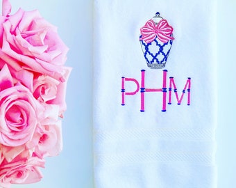 May include: White hand towel with a blue and white ginger jar design and a pink bow. The towel is embroidered with the monogram "PHM" in pink and blue.