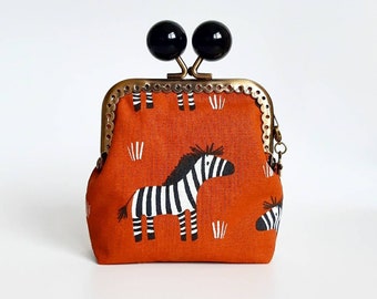 Women's purse with gold metal closure and black balls, small brick-colored fabric wallet with zebra print and clip closure