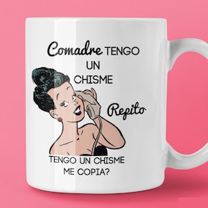 Pu&ograve; includere: Tazza in ceramica bianca con un'illustrazione retr&ograve; di una donna al telefono e il testo spagnolo "Comadre TENGO UN CHISME Repito TENGO UN CHISME ME COPIA?" in nero. La tazza ha un manico curvo e il sito web CHICASUNSHINE.COM.