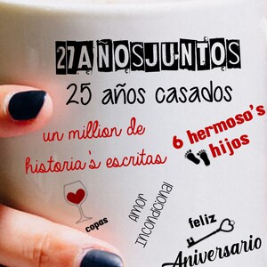 Puede incluir: Taza de cer&aacute;mica blanca con texto negro y rojo, sostenida por una persona. La taza presenta frases como "27 a&ntilde;os juntos", "25 a&ntilde;os casados" y "Feliz Aniversario". El texto adicional incluye "Jacky & Javier" con un s&iacute;mbolo de coraz&oacute;n.