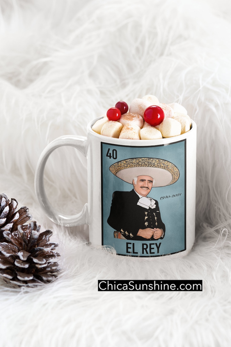 May include: White ceramic mug featuring a portrait of a man in a charro suit, with the text "El Rey". The mug is filled with marshmallows and red berries. The website ChicaSunshine.com is printed at the bottom.