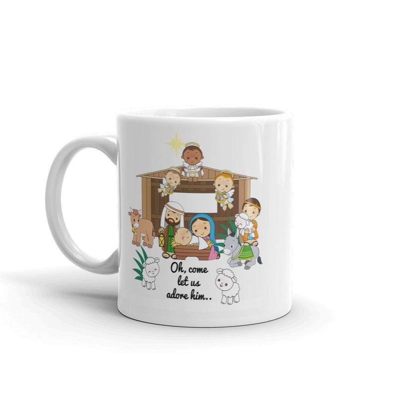 May include: White ceramic mug featuring a Nativity scene illustration. The design includes a stable, angels, and the text "Oh, come let us adore him..". The mug has a curved handle and is suitable for hot beverages.