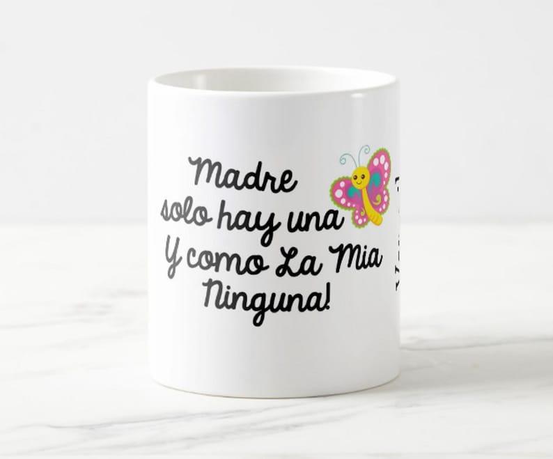 May include: White ceramic mug with black script text that reads "Madre solo hay una y como La Mia Ninguna!" A colorful butterfly graphic with pink, yellow, and blue accents is on the right side of the mug.