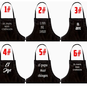 Pu&ograve; includere: Grembiuli neri con testo bianco. I grembiuli presentano frasi in spagnolo come "EL PAPA MAS CHINGON" e "EL JEFE". Ogni grembiule &egrave; numerato in rosso, da 1 a 6.