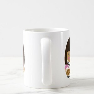 May include: White ceramic mug featuring a cartoon illustration of a person holding a concha pastry. The text "Pan con concha" is written on the mug in black script. The illustration has brown hair and a pink and brown pastry.