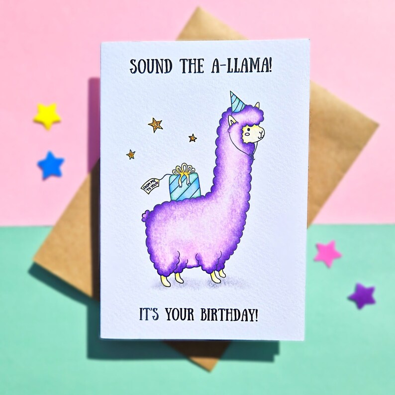 Puede incluir: Una tarjeta de cumplea&ntilde;os con una llama morada que lleva un gorro de fiesta y lleva un regalo. La tarjeta dice "Sound the A-Llama! It's your birthday!"