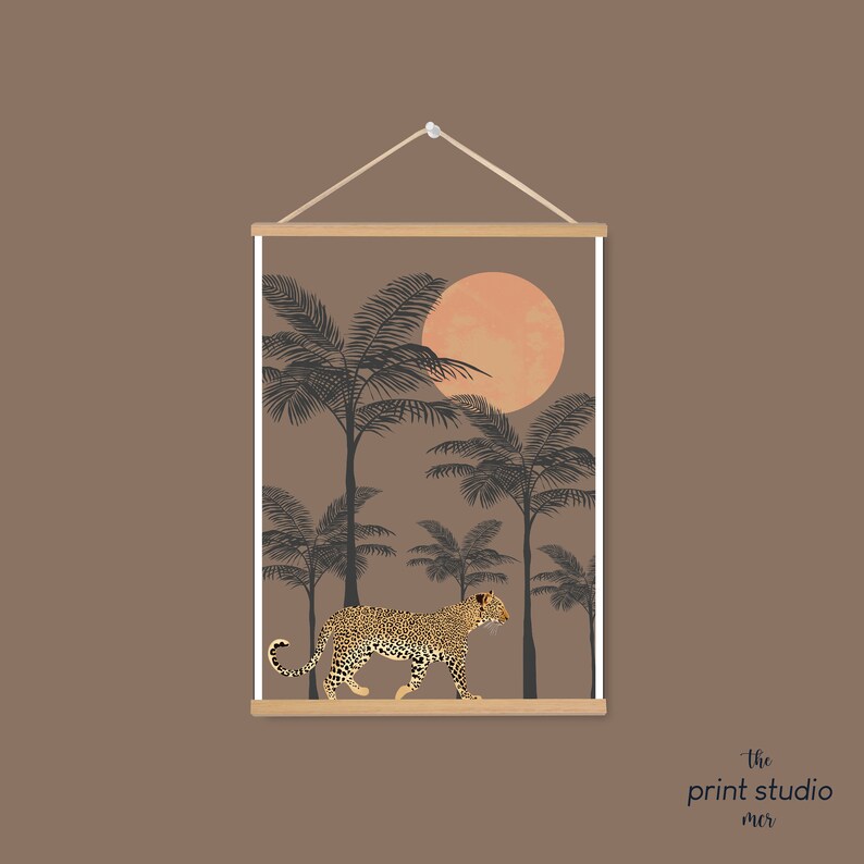 May include: A digital print featuring a leopard walking through a jungle scene with palm trees and a large orange sun. The print is framed with a wooden frame and has the text "the print studio" at the bottom.