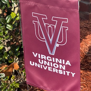 May include: Maroon flag featuring the Virginia Union University logo in white. The logo shows a stylized "V" with the words "VIRGINIA UNION UNIVERSITY" below. The flag is displayed outdoors.