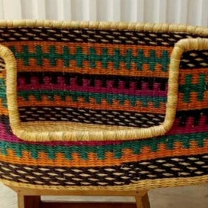 May include: A woven pet bed with a colorful geometric pattern in shades of orange, green, purple, and black. The bed has a thick, woven rim and a raised edge.