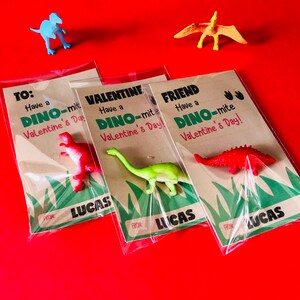 May include: Three Valentine's Day cards with dinosaur toys attached. Each card has a different message: "To: Have a Dino-mite Valentine's Day!"  "Valentine: Have a Dino-mite Valentine's Day!" and "Friend: Have a Dino-mite Valentine's Day!" Each card is signed "From: Lucas".