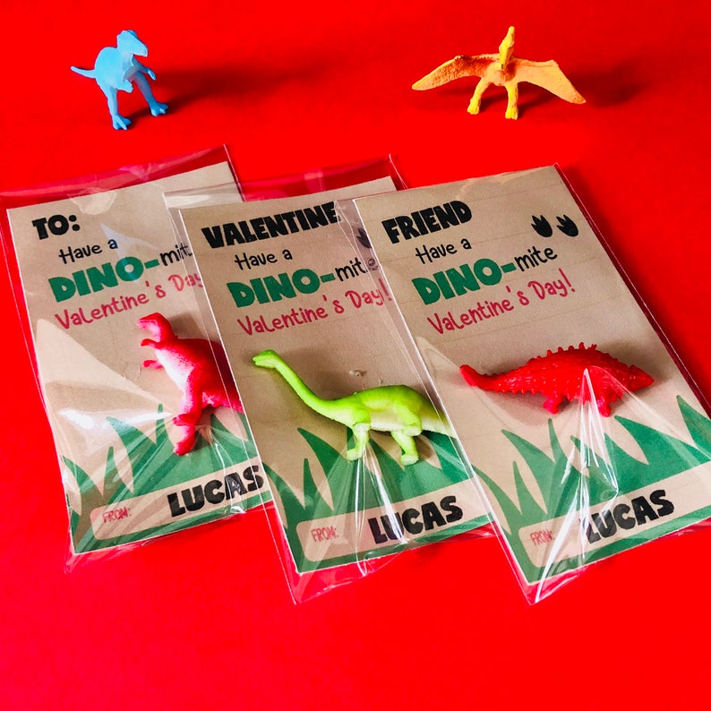 May include: Three Valentine's Day cards with dinosaur toys attached. Each card has a different message: "To: Have a Dino-mite Valentine's Day!"  "Valentine: Have a Dino-mite Valentine's Day!" and "Friend: Have a Dino-mite Valentine's Day!" Each card is signed "From: Lucas".