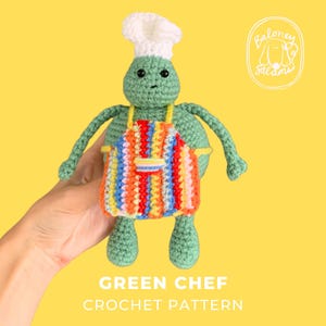 Pode incluir: Uma boneca de crochê verde usando um chapéu de chef branco e um avental listrado colorido com um pequeno bolso. A boneca tem olhos de contas pretas e braços e pernas finos. O texto "GREEN CHEF CROCHET PATTERN" e um logotipo "Baloney Salami" são visíveis.