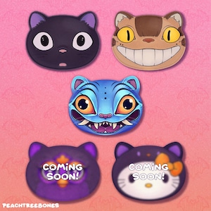 May include: Five cat-themed designs on a pink background. The designs include a black cat, a brown cat with a wide grin, a blue cat with sharp teeth, and two purple and black cat designs with the text "COMING SOON!"