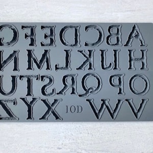 May include: Gray silicone alphabet mold with uppercase letters A through Z. The mold is designed for baking and crafting.