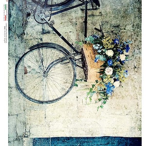 May include: A vintage bicycle with a basket full of flowers. The bicycle is leaning against a textured wall with a blue and white painted section at the bottom. The bicycle is black with a brown leather seat.