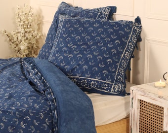 Puede incluir: Una funda nórdica azul y blanca con estampado y ribete de flecos. La funda nórdica está en una cama con dos fundas de almohada a juego.