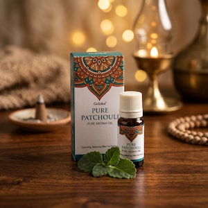 May include: A small brown glass bottle of Goloka Pure Patchouli aroma oil with a white cap, standing next to its matching rectangular cardboard box. The packaging features a colorful mandala design, green accents, and the text Pure Patchouli.