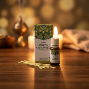 Könnte beinhalten: Eine kleine braune Glasflasche mit Goloka Indian Citronella reinem Aromaöl und weißem Verschluss, die neben der passenden rechteckigen Pappschachtel steht. Ein kleiner Haufen dünner, heller getrockneter Grashalme liegt vor der Verpackung.