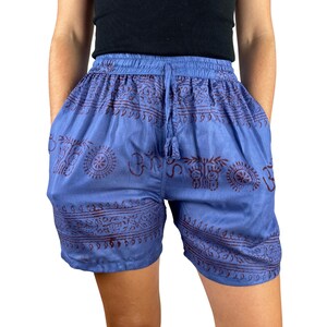 Può includere: Pantaloncini blu con vita con coulisse e tasche. I pantaloncini presentano un motivo ripetuto di simboli e disegni rosso scuro. I pantaloncini sono realizzati in un tessuto leggero.